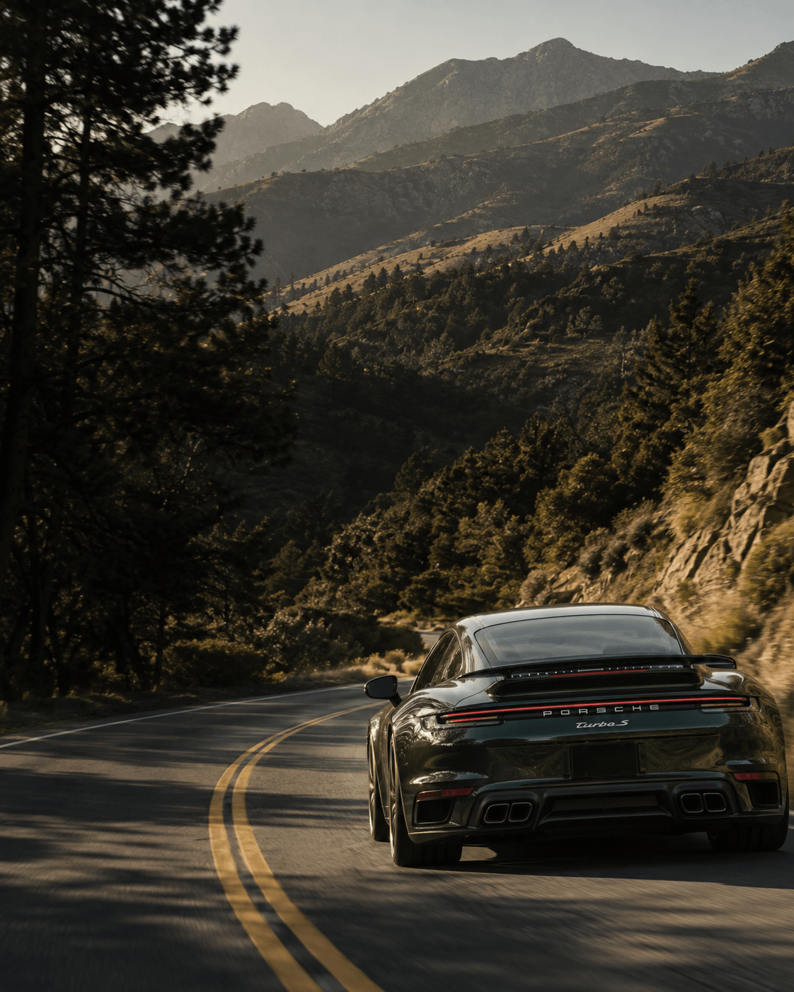 A Porsche 911 on a mountain road at golden hour