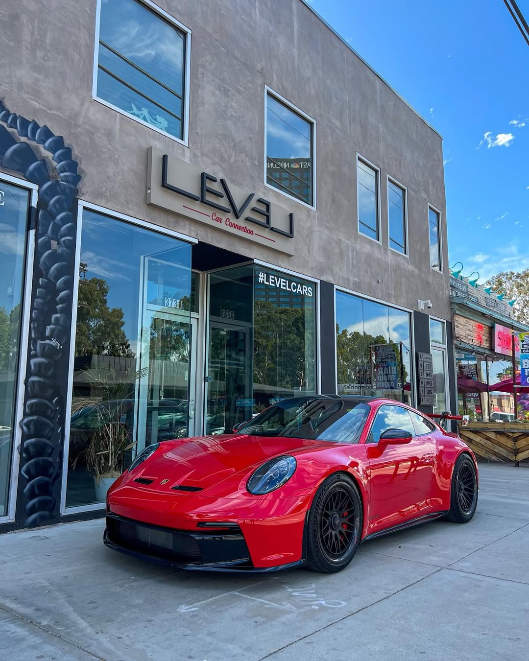 Red Porsche 911 GT3 in front of the LEVEL storefront